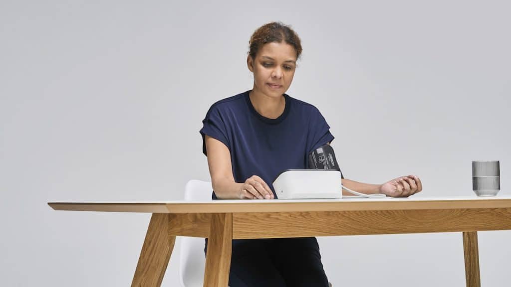 Woman measuring blood pressure sitting at desk